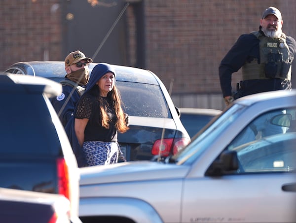 Law officials escort a woman out of an apartment complex during a raid Wednesday, Feb. 5, 2025, in east Denver. (AP Photo/David Zalubowski)