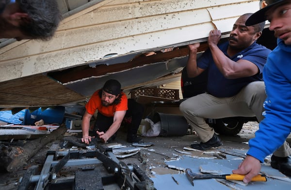 Matt Wolff, left, works underneath his carport with the help of his father-in-law Dempsey Watson and friend Tyler Umbright, right, as they work to stabilize after a severe storm in Bridgeton, Mo., Saturday, March 15, 2025. (Robert Cohen/St. Louis Post-Dispatch via AP)