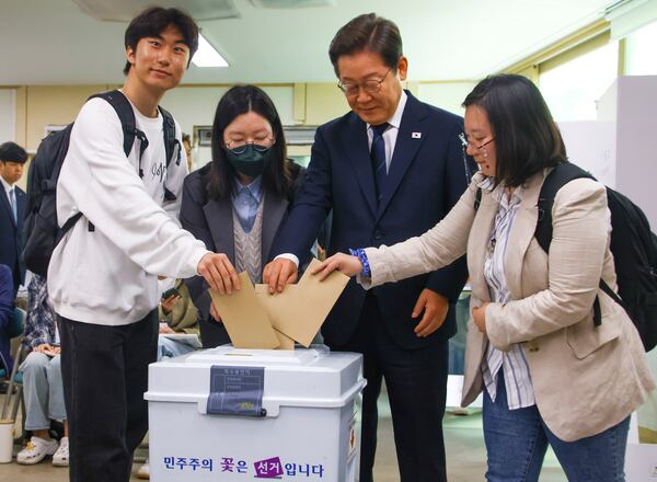 South Korean Democratic Party's presidential candidate Lee Jae-myung, second from right, and young people cast their early votes for the June 3 presidential election at a polling station in Seoul, South Korea, Thursday, May 29, 2025. (Yonhap via AP)