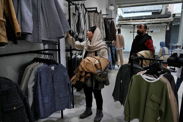 A woman selects clothes as her husband looks on at a shop in port city of Bandar Anzali in northern Iran, Thursday, Dec. 5, 2024. (AP Photo/Vahid Salemi)