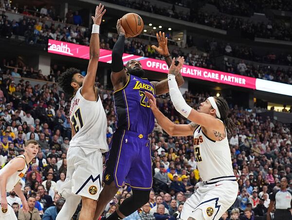 Los Angeles Lakers forward LeBron James, center, drives to the basket as Denver Nuggets guard Jamal Murray, left, and forward Aaron Gordon defend in the first half of an NBA basketball game Saturday, Feb. 22, 2025, in Denver. (AP Photo/David Zalubowski)