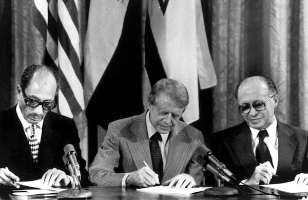 FILE - From left, Egyptian President Anwar Sadat, U.S. President Jimmy Carter, and Israeli Prime Minister Menachem Begin sign one of two agreements forged at the Camp David summit during a joint announcement at the White House on Sept. 17, 1978. (AP Photo, File)