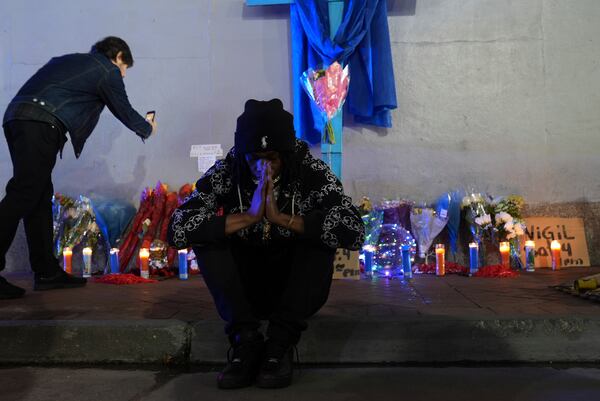 Sav Bennly sits in front of a memorial at Bourbon and Canal Street in the French Quarter, Thursday, Jan. 2, 2025 in New Orleans. (AP Photo/George Walker IV)