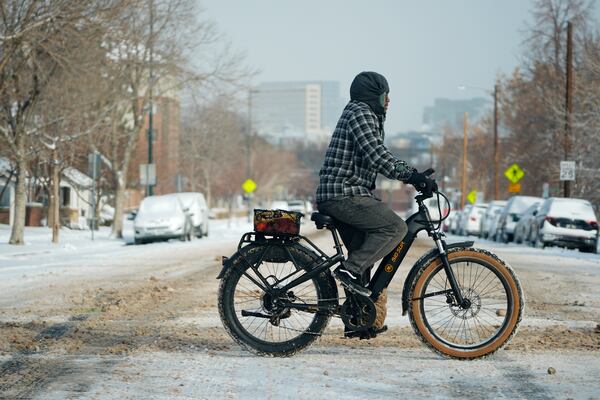 A cyclist navigates 13th Avenue after a winter storm plunged daytime high temperatures into the single digits and left up to six inches of snow in its wake Monday, Jan. 20, 2025, in Denver. (AP Photo/David Zalubowski)