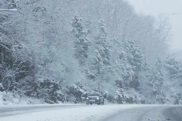 A vehicle makes its way through the snow along U.S. Highway 70 S, Friday, Jan. 10, 2025, in Nashville, Tenn. (AP Photo/George Walker IV)