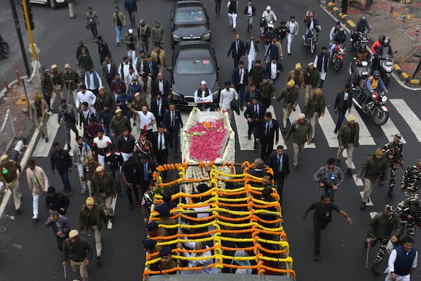 Security officials and others walk with the hearse carrying the body of former Indian Prime Minister Manmohan Singh towards the cremation site in New Delhi, India, Saturday, Dec. 28, 2024. (AP Photo)