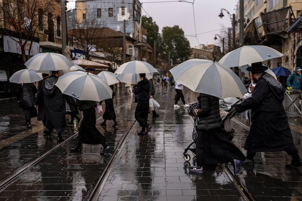 People walk with umbrellas on a rainy day in Jerusalem, Israel, Friday, Dec. 20, 2024. (AP Photo/Ohad Zwigenberg)