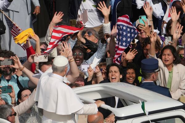 Faithful wave flags of the United States of America as Pope Leo XIV on his popemobile tours St. Peter's Square at the Vatican prior to the inaugural Mass of his pontificate, Sunday, May 18, 2025. (AP Photo/Domenico Stinellis)