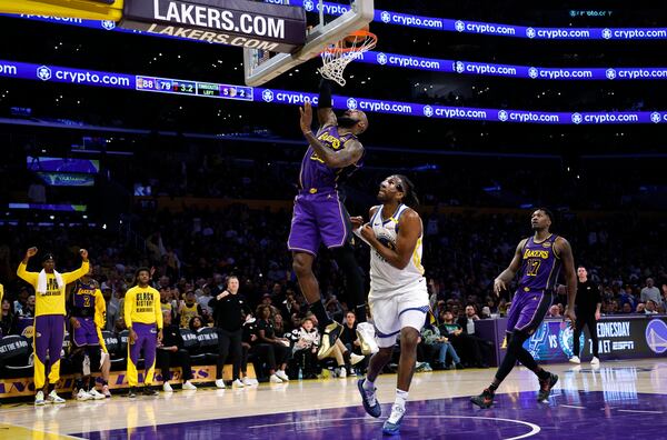 Los Angeles Lakers forward LeBron James scores a basket against Golden State Warriors forward Kevon Looney during the second half of an NBA basketball game Thursday, Feb. 6, 2025, in Los Angeles. (AP Photo/Kevork Djansezian)