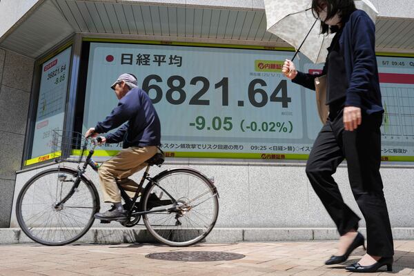 People pass by an electronic stock board showing Japan's Nikkei index at a securities firm Wednesday, May 7, 2025, in Tokyo. (AP Photo/Eugene Hoshiko)