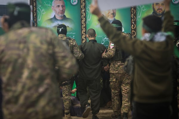 Israeli hostage Omer Wenkert, centre, is escorted by Hamas fighters before being handed over to the Red Cross in Nuseirat, central Gaza Strip, Saturday, Feb. 22, 2025. (AP Photo/Jehad Alshrafi)