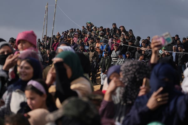 Palestinians gather as Hamas fighters deploy ahead of handing over the bodies of four Israeli hostages, including a mother and her two children, who had long been feared dead, to the Red Cross in Khan Younis, southern Gaza Strip, Thursday, Feb. 20, 2025. (AP Photo/Abdel Kareem Hana)