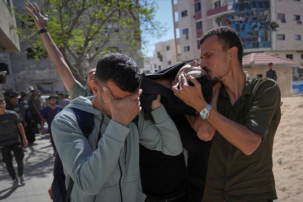 A man kisses the body of a victim of an Israeli army strike on a restaurant, which killed at least 29 people, as he is taken from the scene to the Shifa hospital in Gaza City, Wednesday, May 7, 2025.(AP Photo/Jehad Alshrafi)