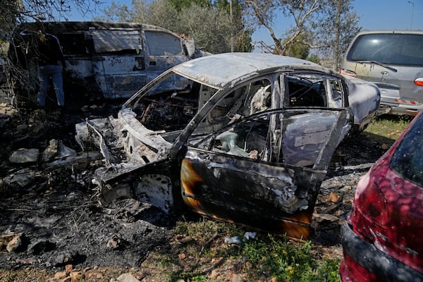 A man inspects a torched vehicle, one of three that were set on fire by attackers overnight in a Palestinian garage in the West Bank village of Umm Safa, north of Ramallah, Tuesday, March 11, 2025. (AP Photo/Nasser Nasser)