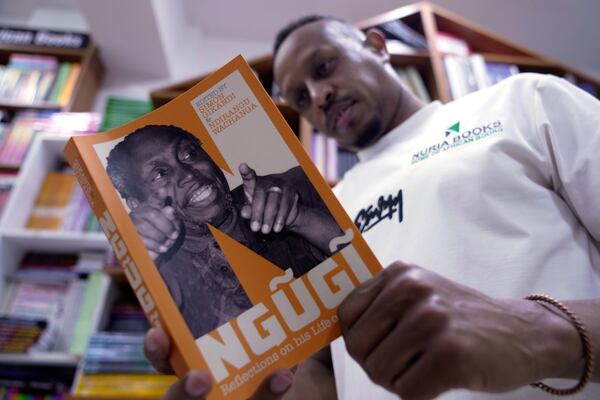Abdullahi Ahmed holds a book of renowned Kenyan writer Ngugi wa Thiong'o, who died Wednesday in the U.S., at Nuria bookshop in Nairobi, Kenya, Thursday, May 29, 2025. (AP Photo/Brian Inganga)
