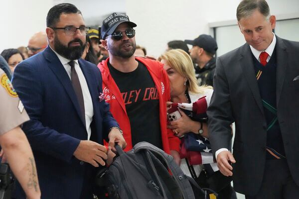 Enrique Tarrio, center, walks with his attorneys after arriving at Miami International Airport, Wednesday, Jan. 22, 2025, in Miami. Tarrio was pardoned by President Donald Trump after he was convicted of seditious conspiracy for his role in the January 6 attack on the U.S. Capitol. (AP Photo/Marta Lavandier)