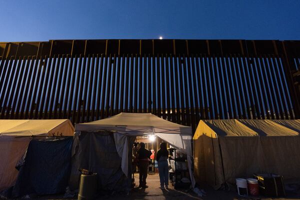 Volunteers talk in a tent along a border wall separating Mexico from the United States Wednesday, Jan. 22, 2025, in San Diego. (AP Photo/Gregory Bull)