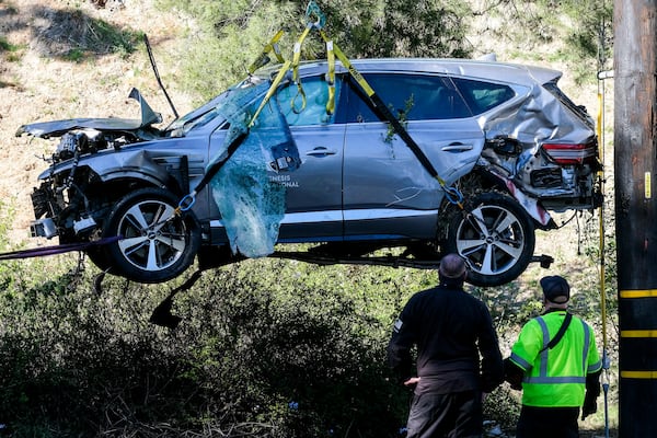 FILE - Workers watch as a crane is used to lift a vehicle following a rollover accident involving golfer Tiger Woods, Feb. 23, 2021, in the Rancho Palos Verdes section of Los Angeles. (AP Photo/Ringo H.W. Chiu, file)