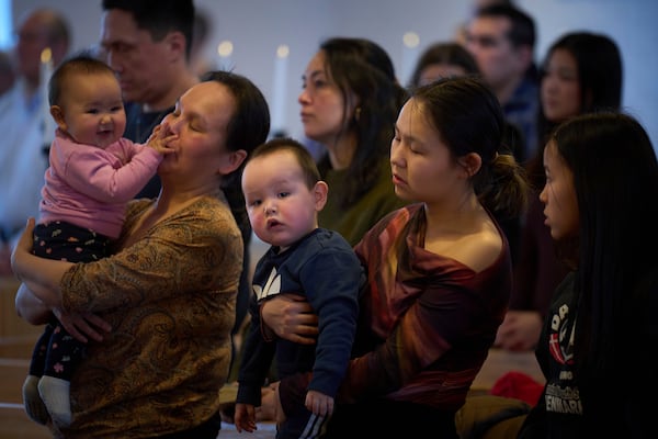 Worshippers hold their children during a religious service at Hans Egede Church in Nuuk, Greenland, Sunday, Feb. 16, 2025. (AP Photo/Emilio Morenatti)