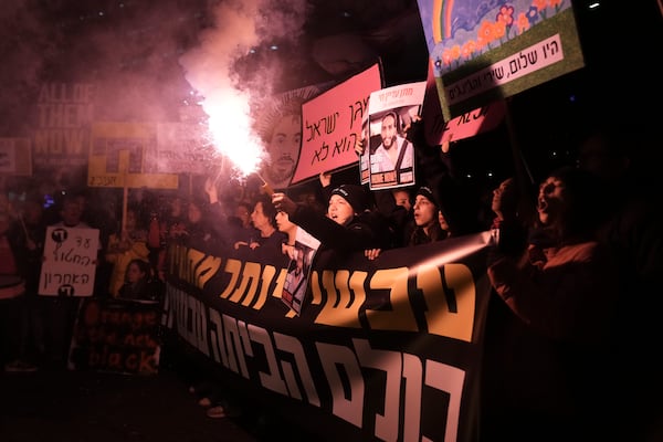 Demonstrators light a flare during a protest demanding the immediate release of hostages held by Hamas in the Gaza Strip, in Tel Aviv, Israel, Saturday, Feb. 22, 2025. (AP Photo/Maya Alleruzzo)