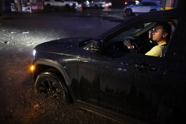 A motorist drives through a mud-covered road in the Palisades Fire zone during a storm Thursday, Feb. 13, 2025, in the Pacific Palisades neighborhood of Los Angeles. (AP Photo/Ethan Swope)