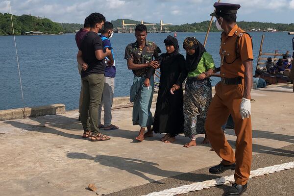 Two women and a man, center, believed to be Rohingya refugees, arrive at a port in Trincomalee, Sri Lanka, Friday, Dec. 20, 2024. (AP Photo/Mangalanath Liyanaarahhi)