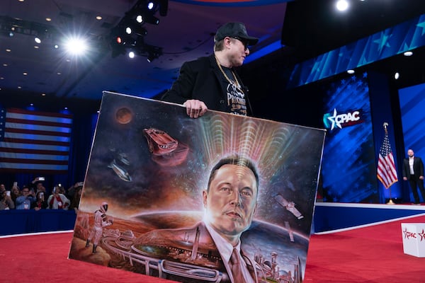 Elon Musk holds a painting after speaking at the Conservative Political Action Conference, CPAC, at the Gaylord National Resort & Convention Center, Thursday, Feb. 20, 2025, in Oxon Hill, Md. (AP Photo/Jose Luis Magana)