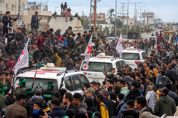 Palestinians gather as Hamas fighters escort Red Cross vehicles carrying Israeli captives Ohad Ben Ami, Eli Sharabi, and Or Levy, who have been held hostage by Hamas in Gaza since October 7, 2023, after being handed over in Deir al-Balah, central Gaza Strip, Saturday, Feb. 8, 2025. (AP Photo/Abdel Kareem Hana)