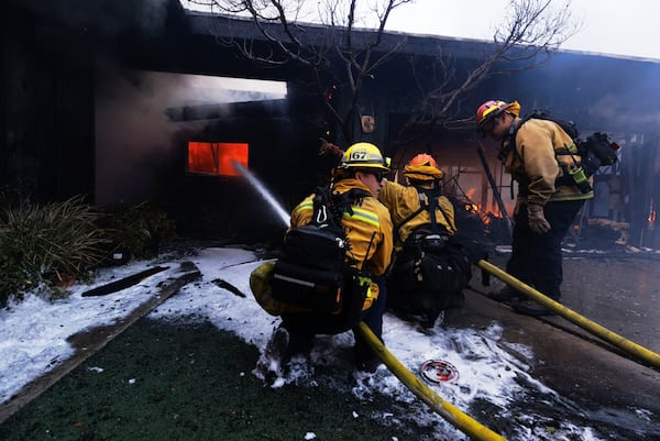 Firefighters battle the advancing Palisades Fire as it damages a residence in the Pacific Palisades neighborhood of Los Angeles, Tuesday, Jan. 7, 2025. (AP Photo/Ethan Swope)