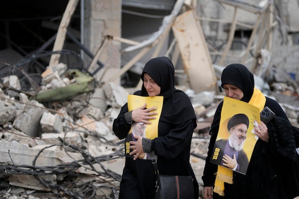 Lebanese women hold portraits of of slain Hezbollah leader Sayyid Hassan Nasrallah, as they check the destruction in their village caused by the Israeli air and ground offensive, in Aita al-Shaab, a Lebanese border village with Israel, south Lebanon, Sunday, Jan. 26, 2025. (AP Photo/Bilal Hussein)