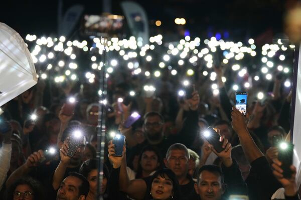 Turkish Cypriot protesters hold the lighted mobile phones aloft as as they gather to protest against what they say is Turkey's attempt to erode their secular roots and to strengthen the hold of political Islam over their society, in the northern half of ethnically divided Cyprus' capital Nicosia, on Friday, May 2, 2025. (AP Photo/Petros Karadjias)