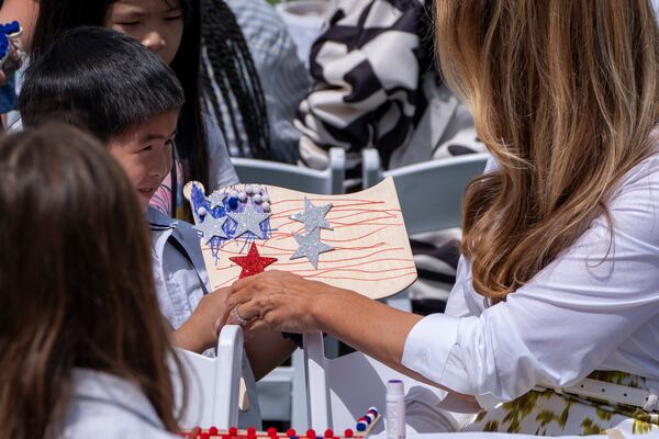 First lady Melania Trump looks at a decorated flag as she participates in flag decorating during a Take Our Child to Work Day event in the Jacqueline Kennedy Garden at the White House, Tuesday, May 20, 2025, in Washington. (AP Photo/Alex Brandon)