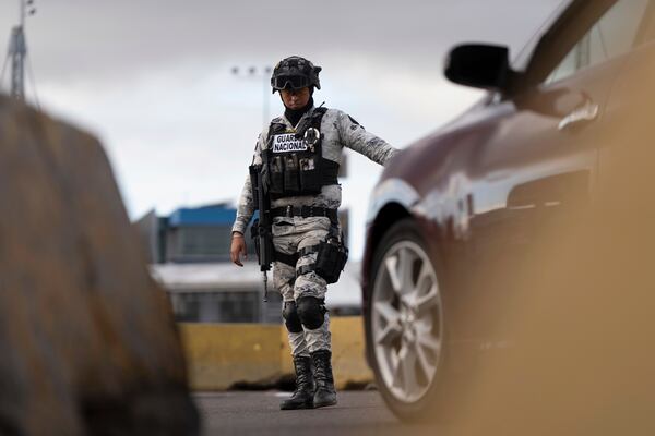 Members of Mexico's National Guard stand guard at an inspection checkpoint for cars in line to cross the border into the United States from Mexico at the San Ysidro Port of Entry, Thursday, Feb. 6, 2025, in Tijuana, Mexico. (AP Photo/Gregory Bull)