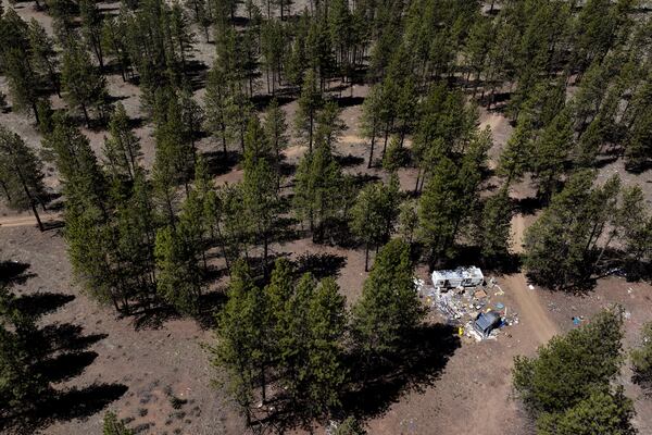 Debris lies scattered around a trailer at a homeless encampment in Deschutes National Forest, Thursday, May 1, 2025, near Bend, Ore. (AP Photo/Jenny Kane)