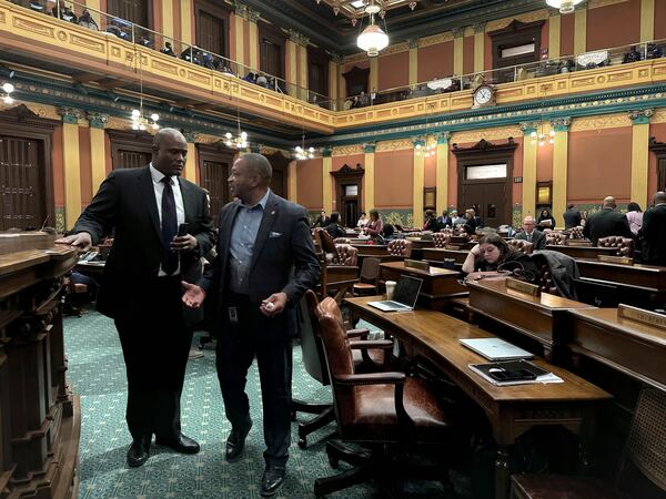 Michigan House Democratic Speaker Joe Tate, left, and state Representative Tyrone Carter, a Democrat, speak on the floor of the Michigan House of Representatives in Lansing, Mich., Thursday, Dec. 19, 2024. Internal divisions caused House Democrats to effectively end the legislative session for the chamber and their historic time in power Thursday. (AP Photo/Isabella Volmert)