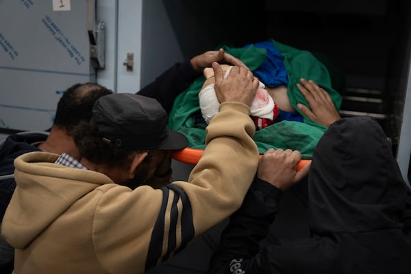 Relatives of Palestinian Imran Haroun, touch his body at the hospital morgue after he was killed during a military operation in the Tulkarem refugee camp near the West Bank city of Tulkarem, Wednesday, Dec. 25, 2024. (AP Photo/Majdi Mohammed)