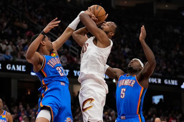 Cleveland Cavaliers forward Evan Mobley, center, is fouled by Oklahoma City Thunder guard Aaron Wiggins (21), left, as he goes to the basket between Wiggins and Luguentz Dort (5) in the first half of an NBA basketball game, Wednesday, Jan. 8, 2025, in Cleveland. (AP Photo/Sue Ogrocki)