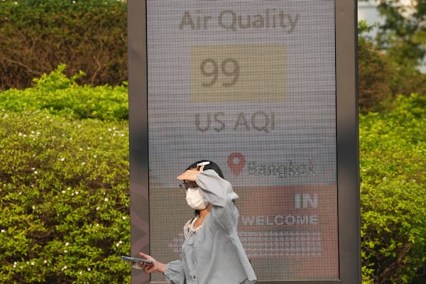 FILE - A pedestrian wears a face mask in front of a sign displaying an Air Quality Index in Bangkok, Thailand, Feb. 6, 2025. (AP Photo/Sakchai Lalit, File)