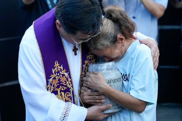 Filipino Catholic priest Flavie Villanueva, left, consoles Melinda Lafuente, as she holds the urn containing the remains of her son Angelo, during an interment ceremony for victims of extrajudicial killings, at the "Dambana ng Paghilom" or Shrine of Healing inside a cemetery in Caloocan City, Philippines, Wednesday March 12, 2025. (AP Photo/Aaron Favila)