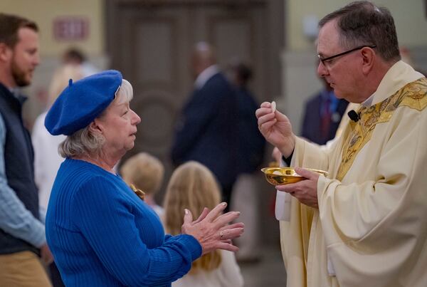 Father Patrick Williams gives a blessing and Eucharist bread to a parishioner at St. Louis Cathedral during a mass about the victims of the New Year's Day deadly truck attack and shooting on Bourbon Street not far from the cathedral in the French Quarter in New Orleans, Sunday, Jan. 5, 2025. (AP Photo/Matthew Hinton)