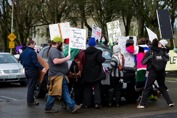 People stand in front of a driver attempting to continue past a protest against the Trump administration and Project 2025 near the Washington State Capitol building Wednesday, Feb. 5, 2025, in Olympia, Wash. (AP Photo/Lindsey Wasson)