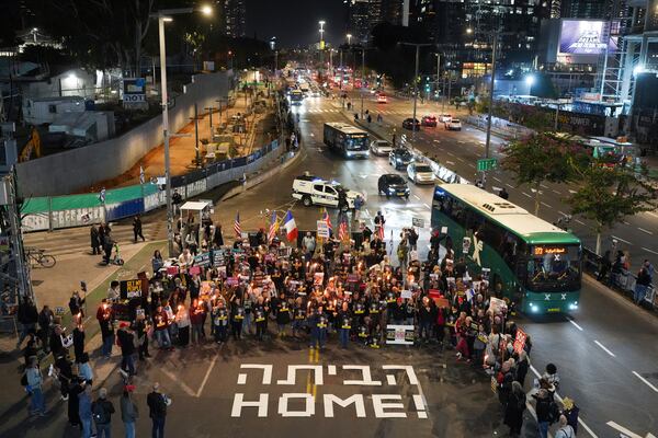 Demonstrators hold torches during a protest calling for the immediate release of the hostages held in the Gaza Strip by the Hamas militant group in Tel Aviv, Israel, on Monday, Jan. 13, 2025. (AP Photo/Ohad Zwigenberg)