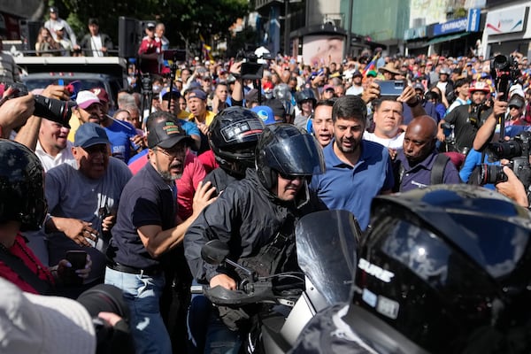 Opposition leader Maria Corina Machado, wearing a helmet, sits on the back of a motorcycle as she is driven away after addressing people at a protest against President Nicolas Maduro in Caracas, Venezuela, Thursday, Jan. 9, 2025, the day before his inauguration for a third term. (AP Photo/Matias Delacroix)