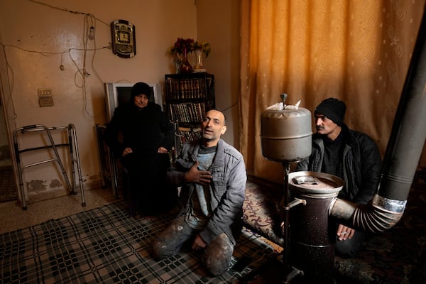 Hussein Arbeeni, 41, centre, sits between his mother mother Khadija Dabbas, 66, left, and his brother Hassan Arbeeni, 42, right, explains how he suffered from the sarin struck during a 2013 chemical weapons attack that was blamed on then President Bashar Assad's forces, in Zamalka neighbourhood, on the outskirts of Damascus, Syria, Wednesday, Dec. 25, 2024. (AP Photo/Hussein Malla)