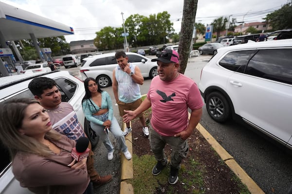 FILE - Henry Carmona, 48, right, who fled Venezuela after receiving death threats for refusing to participate in demonstrations in support of the government, stands with friends and a reporter following a press conference by Venezuelan community leaders to denounce changes to the protections that shielded hundreds of thousands of Venezuelans, including Carmona, from deportation, Monday, Feb. 3, 2025, in Doral, Fla. (AP Photo/Rebecca Blackwell, File)