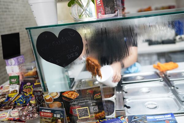An employee serves up shredded beef for a customer inside a franchise of "Sabor Venezolano," one of 18 businesses owned by Wilmer Escaray which employ scores of Venezuelan immigrants with Temporary Protected Status (TPS) who are now potentially exposed to deportation, in Doral, Fla., Tuesday, May 20, 2025. (AP Photo/Rebecca Blackwell)
