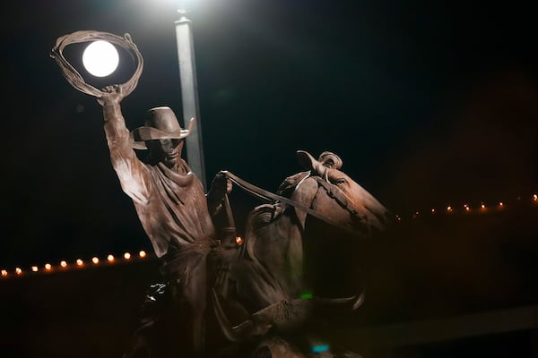 The full moon is seen through the lasso of statue depicting a cowboy roping cattle near the Oklahoma National Stockyards Monday, Jan. 13, 2025, in Oklahoma City. (AP Photo/Julio Cortez)