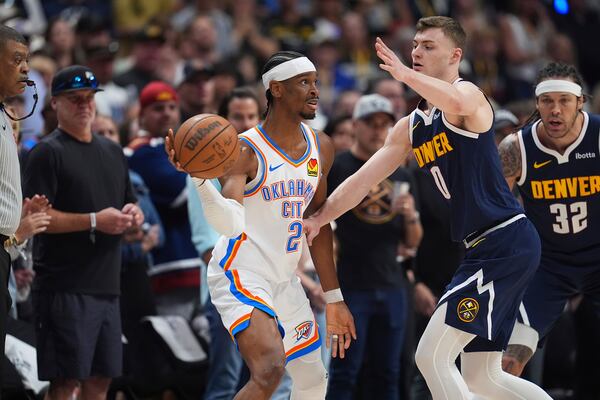 Oklahoma City Thunder guard Shai Gilgeous-Alexander (2) looks to pass the ball as Denver Nuggets guard Christian Braun (0) defends in the first half of Game 4 in the Western Conference semifinals of the NBA basketball playoffs Sunday, May 11, 2025, in Denver. (AP Photo/David Zalubowski)