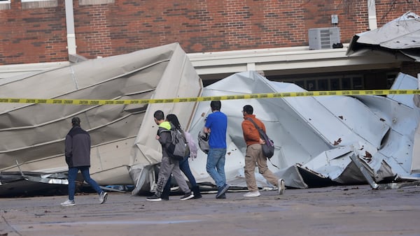 Students arriving for classes walk past damage from the roof that was sheered off by high by winds at Plano West High School Tuesday, March 4, 2025, in Plano, Texas. (AP Photo/LM Otero)