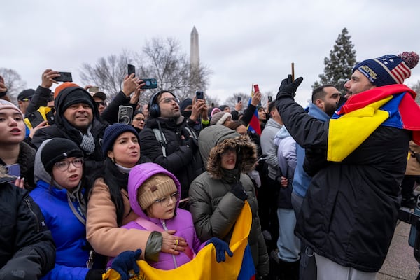 A man wearing a hat for President-elect Donald Trump's inauguration records supporters of Edmundo Gonzalez, who represented Venezuela's main opposition coalition in the July presidential election, as they sing outside of the Organization of American States, Monday, Jan. 6, 2025, in Washington. (AP Photo/Jacquelyn Martin)